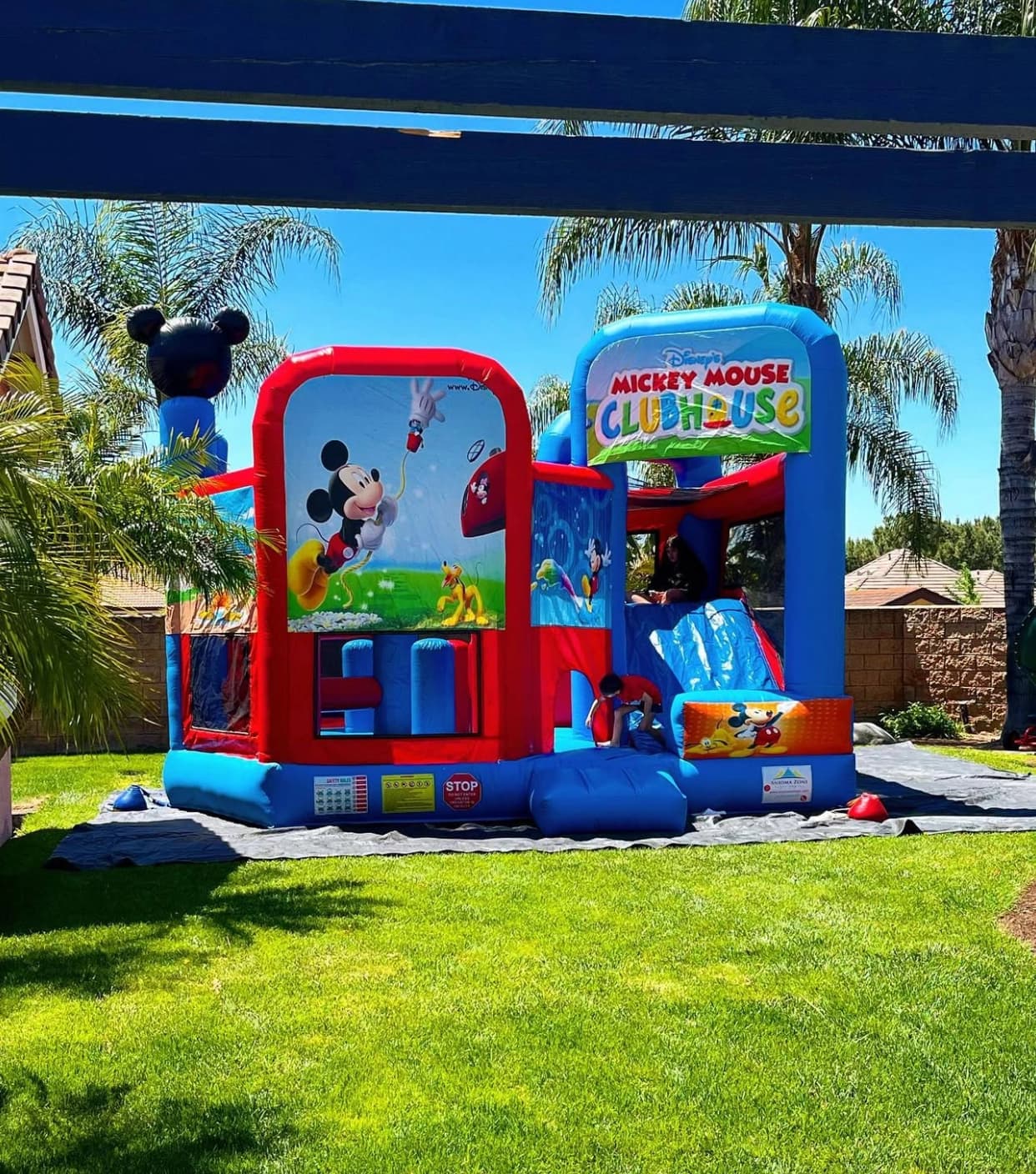 Outdoor front view of the Disney Mickey Mouse 5-in-1 inflatable combo showing the slide and entry area.