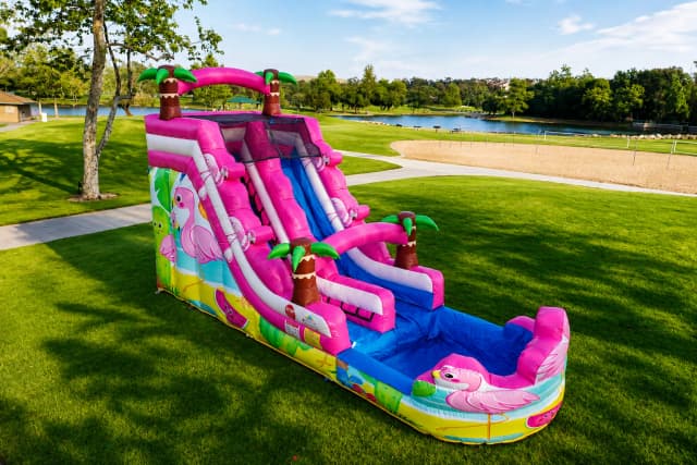Outdoor front angle of the Pink Flamingo Paradise Water Slide showing pink flamingo graphics, palm trees, and splash pool.