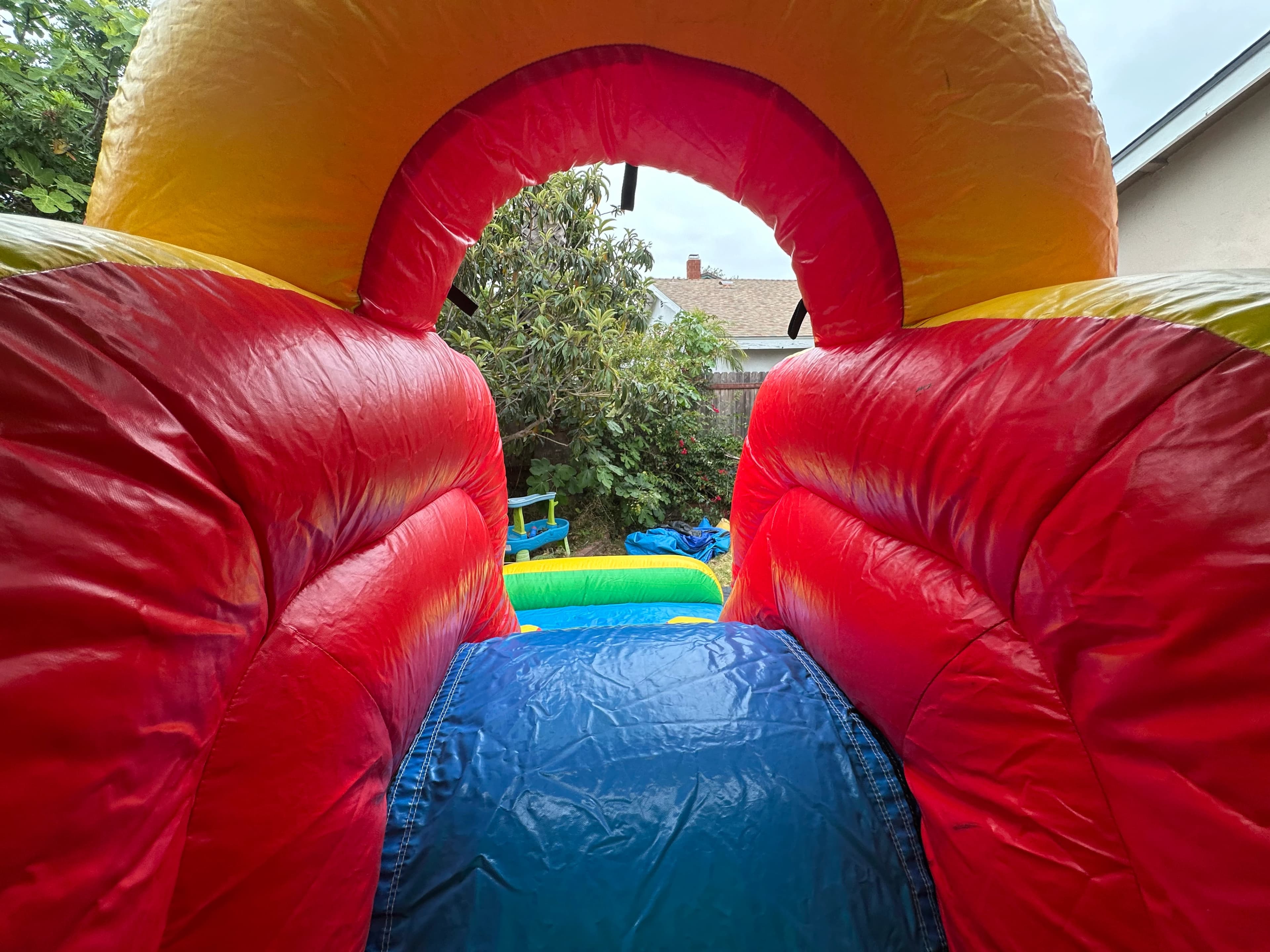 Interior view of the Rainbow Castle Combo showing bounce space, climbing wall, and slide entrance.