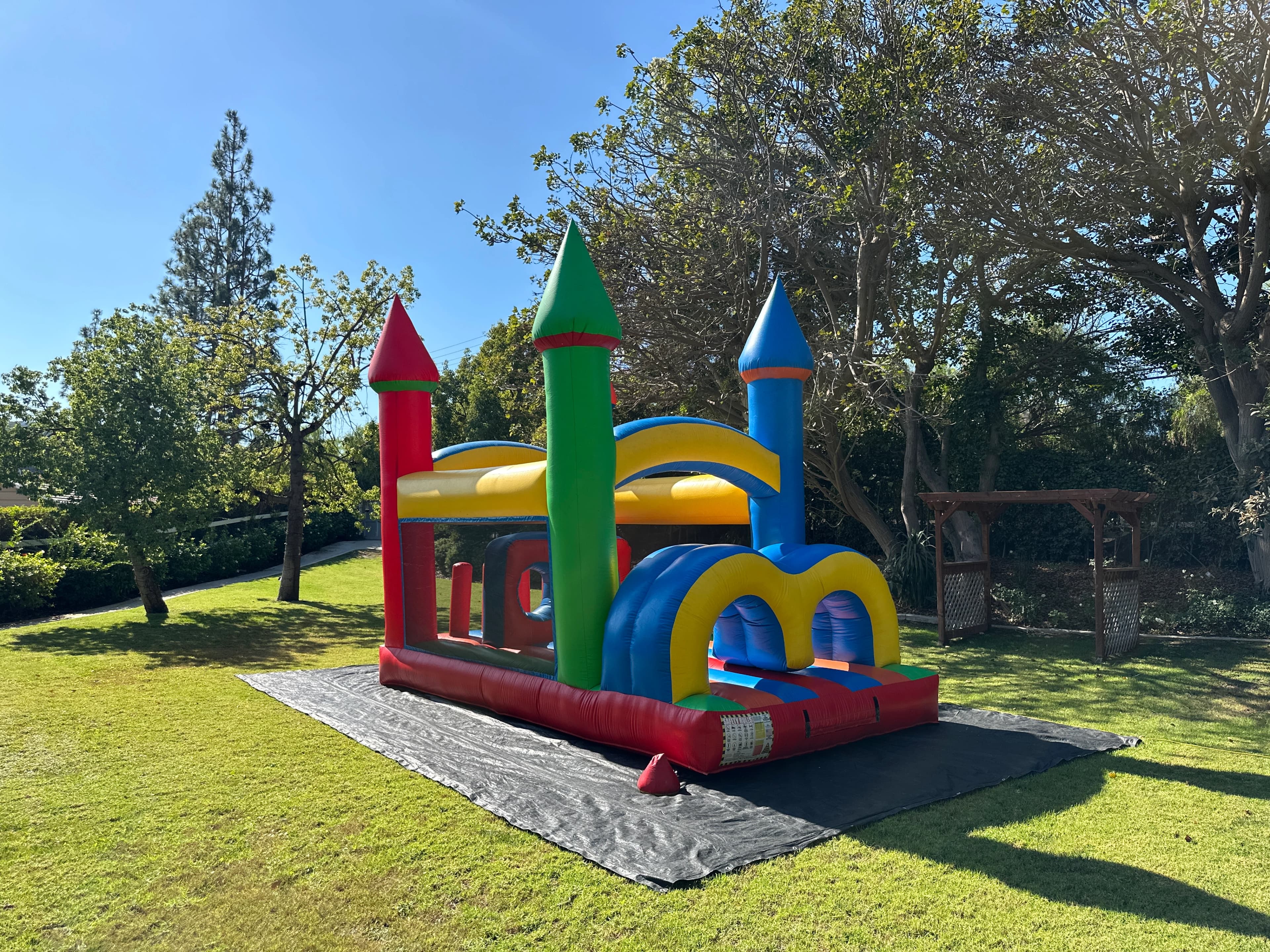Outdoor front angle of the Rainbow Tunnel Rush obstacle course showing entry arches and colorful slide path.