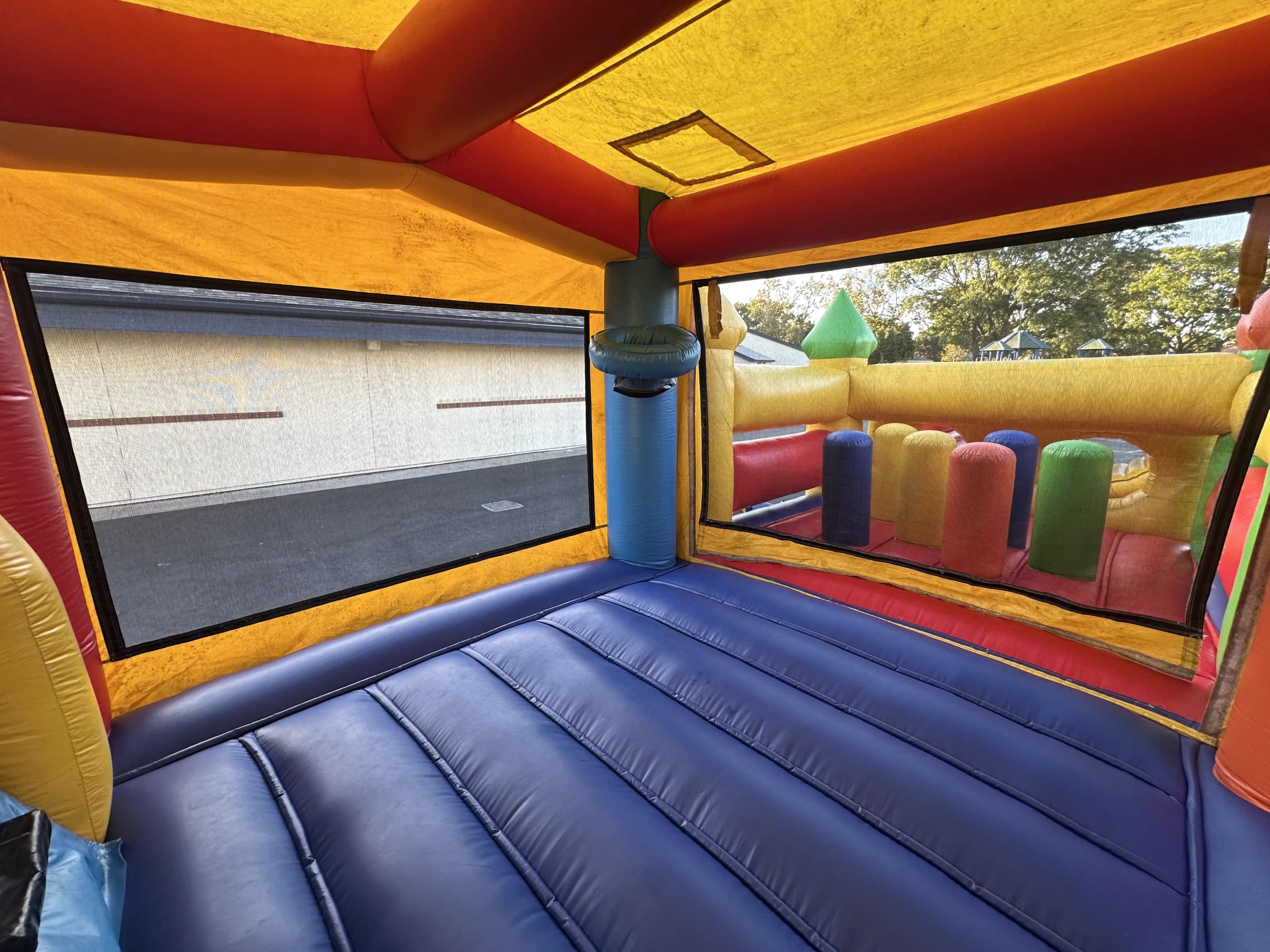 Ground-level interior view of the Super 6 in 2 Fun Run Obstacle Combo showcasing the bounce floor area with mesh walls and overhead netting visible.