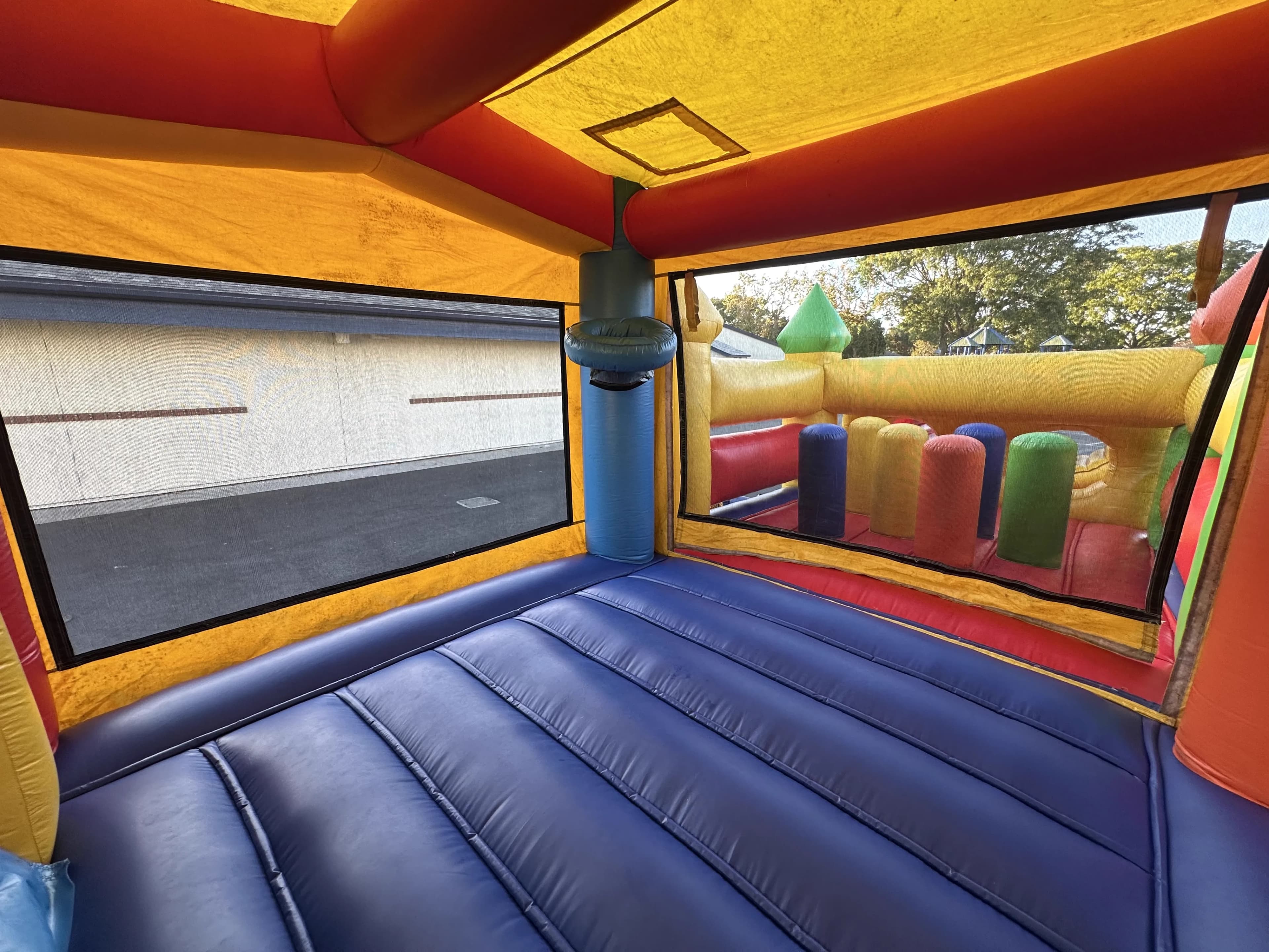 Side perspective inside the enclosed room of the Super 6 in 2 Fun Run Obstacle Combo showing the wall structure and connecting tunnel opening.
