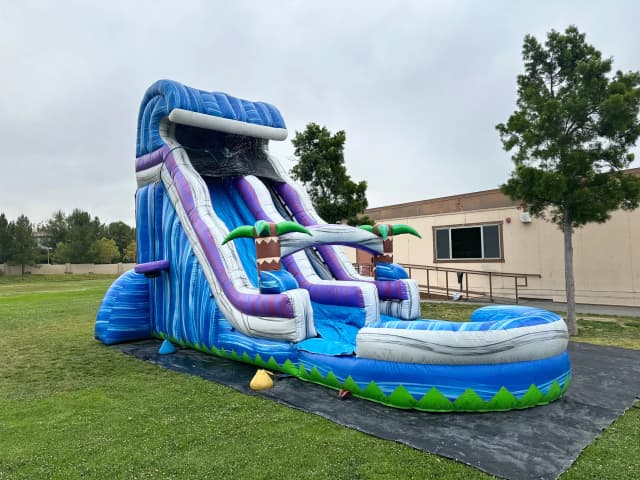 Outdoor front angle of the Tropical Surge 22-Foot water slide showing extended splash pool and dual palm arches.