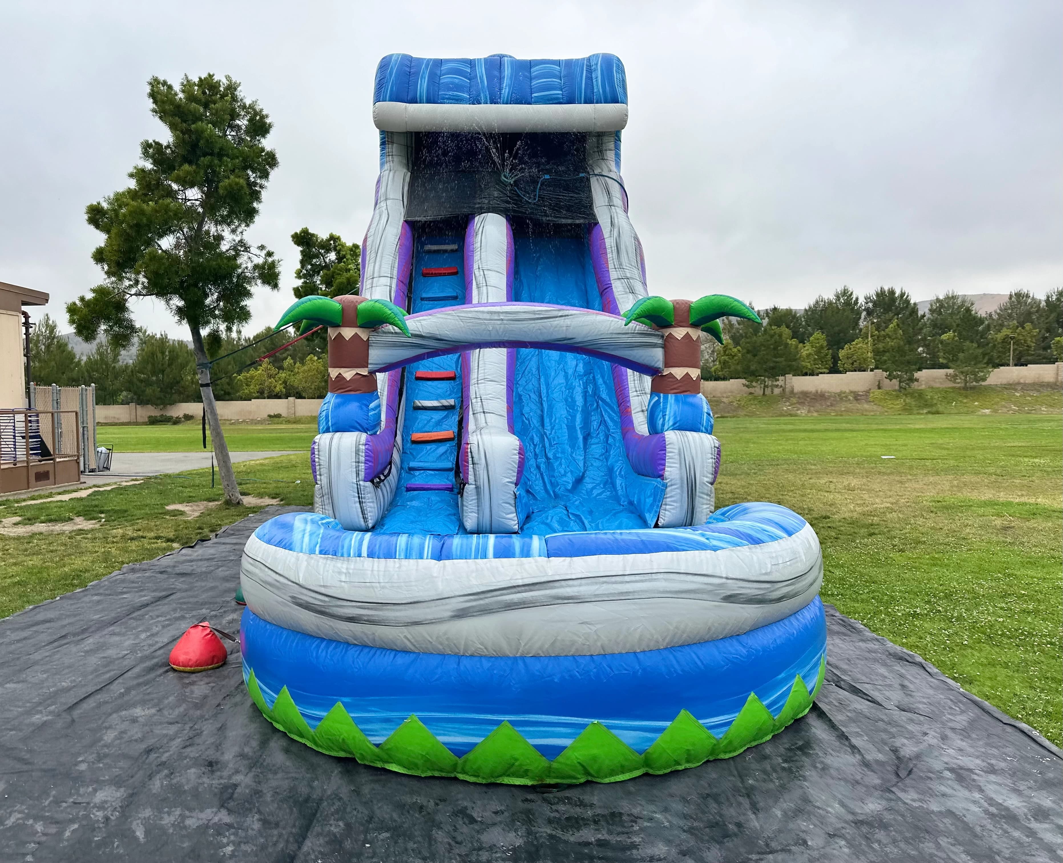 Wide right-side angle of the Tropical Surge 22-Foot water slide showing ladder, slide lanes, and curved pool.