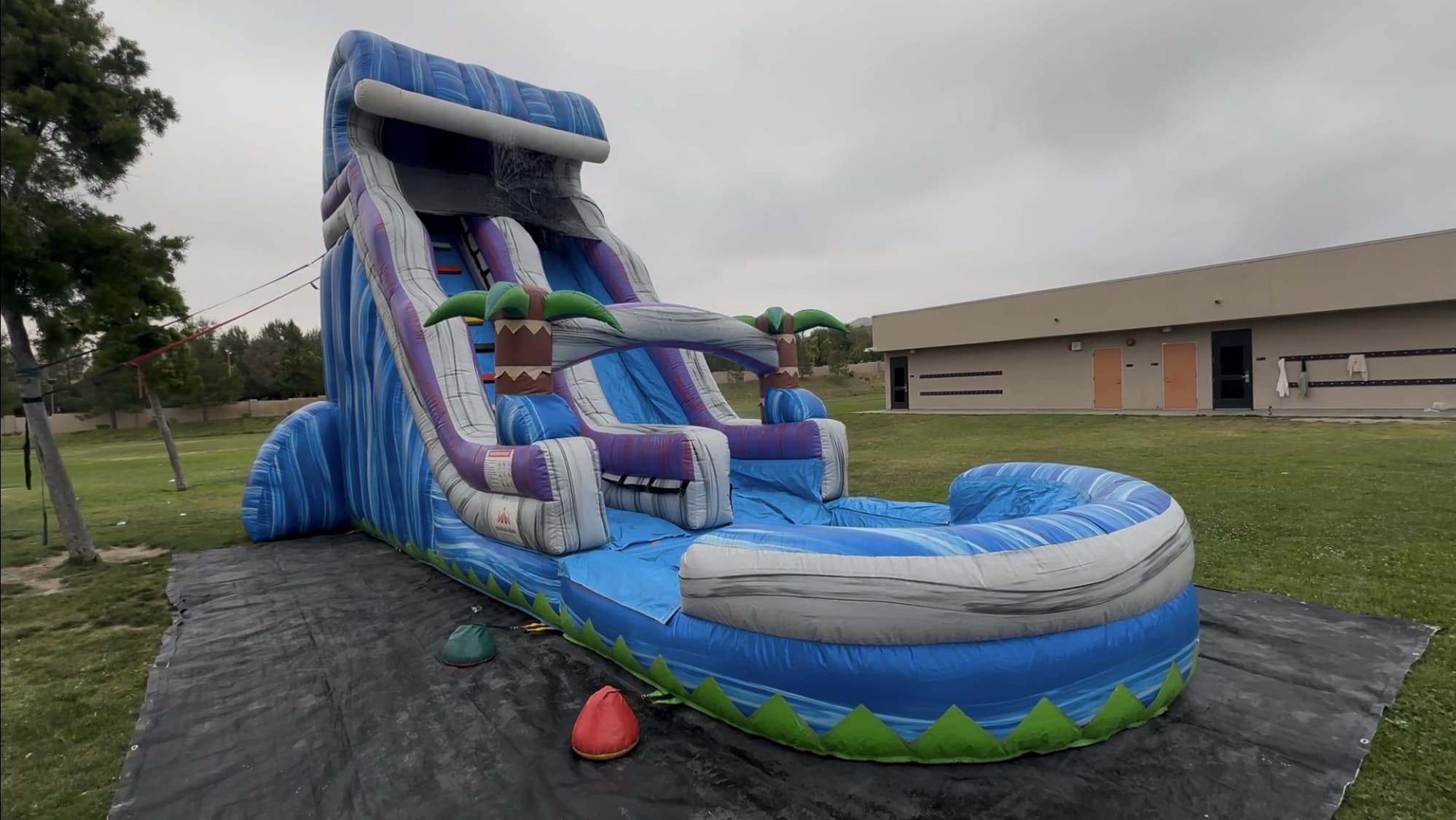Close-up of the Tropical Surge 22-Foot water slide palm arch with integrated water sprayer over the lanes.