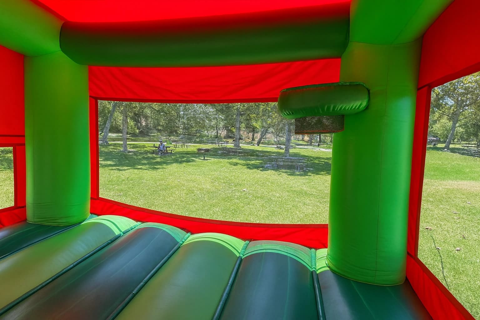 Interior basketball hoop feature inside the Watermelon Wonder bounce house with green columns and red walls.